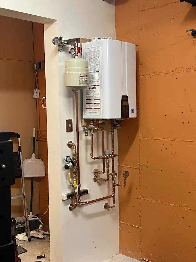 Plumbing technician inspecting water heater connections in Adelphi